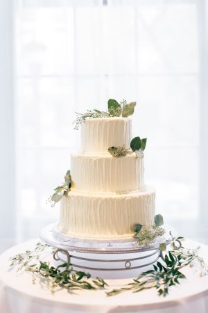 White buttercream wedding cake with greenery - Justina Louise Photography