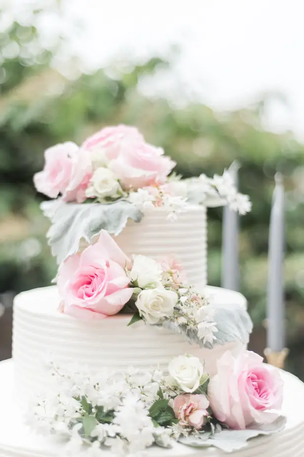 White buttercream wedding cake with fresh flowers and pink rosesLynne Reznick Photography