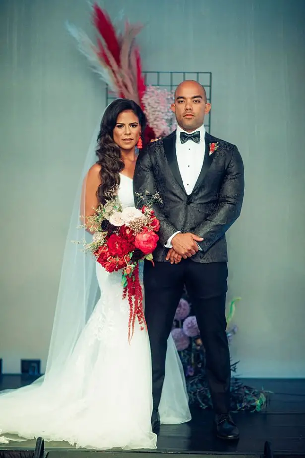 Classic photo of bride and groom with red flowers - Little Honey Photography