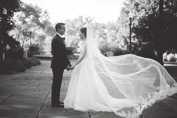 Romantic black and white photo of bride and groom holding hands with veil floating in the wind - Aileen Elizabeth Photography