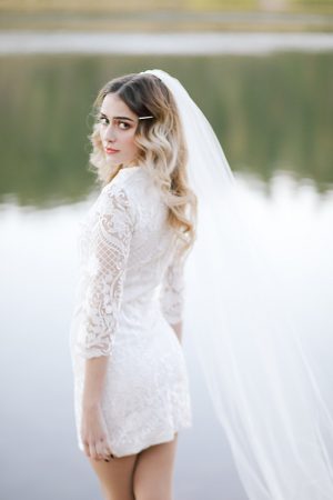 Romantic short lace wedding dress with sleeves and cathedral veil - Photo: Tiffany Hudson Films