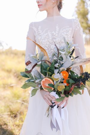 Wedding bouquet with oranges and high neck lace wedding dress with long sleeves - Photo: Tiffany Hudson Films