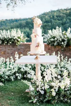 All white wedding cake and cake table surrounded by flowers- Purewhite Photography