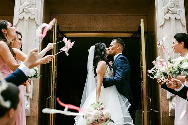 Bride and groom kissing during exit from ceremony with ribbon wands - Bluespark Photography