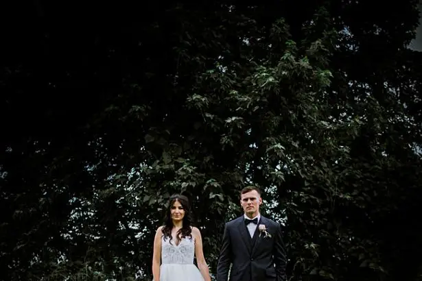 Country Club Wedding epic wide shot of bride and groom in front of trees - Bluespark Photography