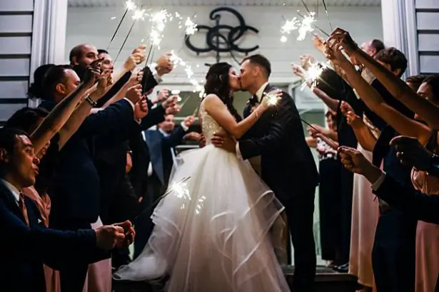 Country Club Wedding sparkler exit photo of bride and groom kissing - Bluespark Photography