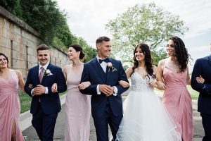 Country Club Wedding with blue and pink photo of bride and groom walking with bridal party - Photography: NST Pictures