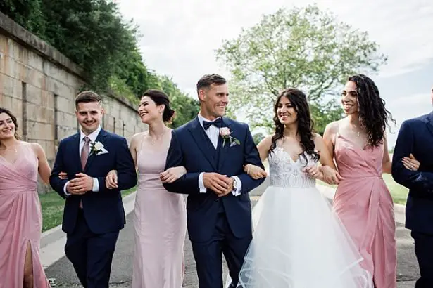 Country Club Wedding with blue and pink photo of bride and groom walking with bridal party - Bluespark Photography