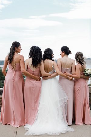 Photo of bride and bridesmaids hugging with long pink bridesmaids dresses - Photography: NST Pictures
