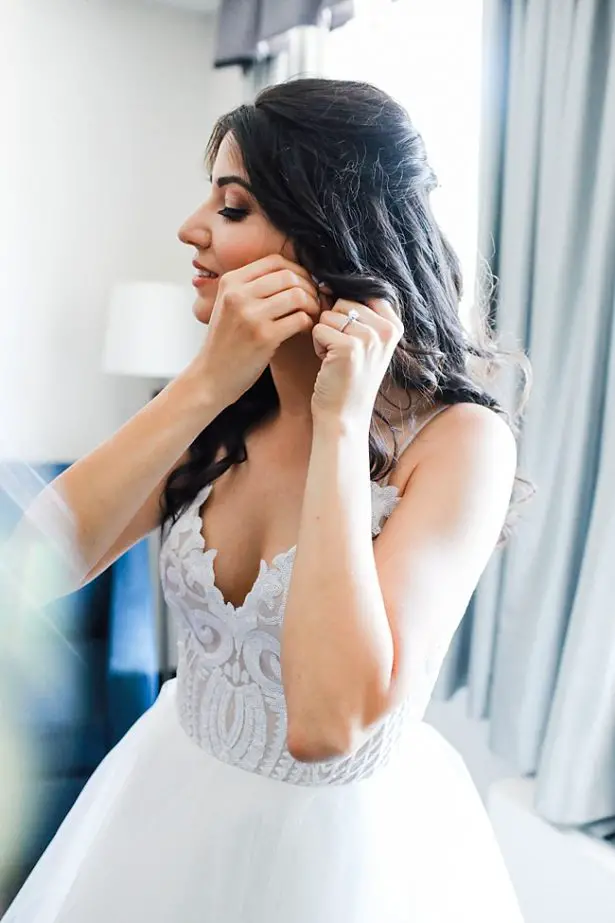 Photo of bride getting ready putting in her earrings - Bluespark Photography