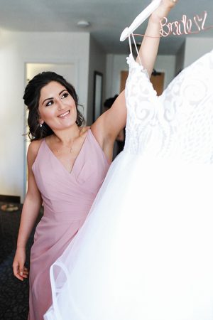 Photo of bridesmaid with brides dress for getting ready - Photography: NST Pictures