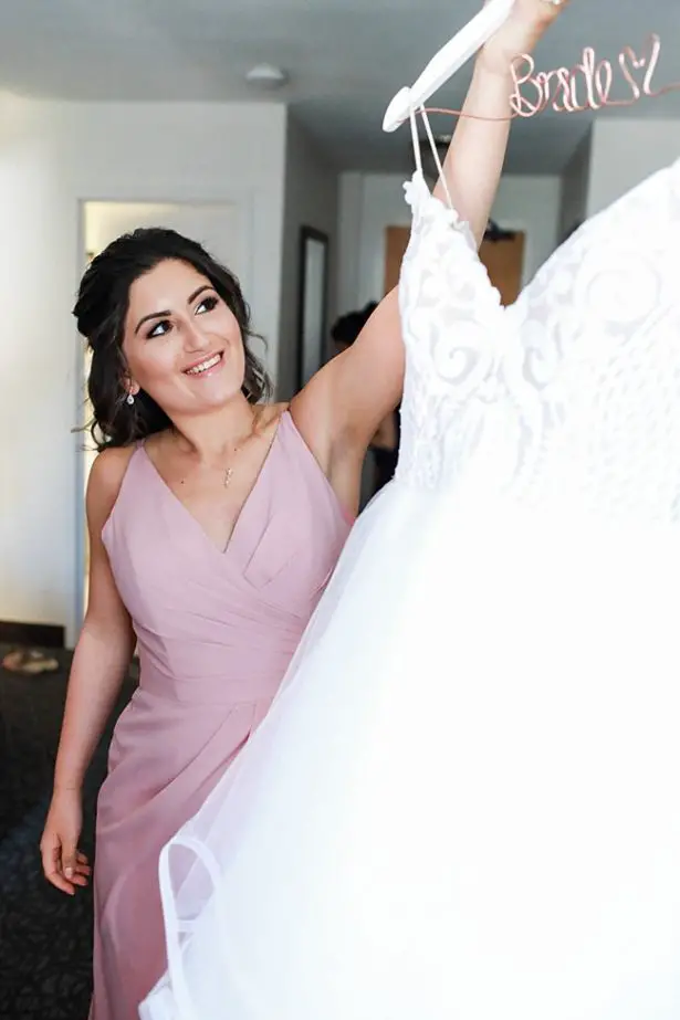 Photo of bridesmaid with brides dress for getting ready - Bluespark Photography
