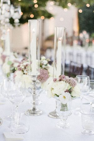 Romantic wedding reception table decor with tall glass candle votives and white and mauve floral centerpieces - Purewhite Photography