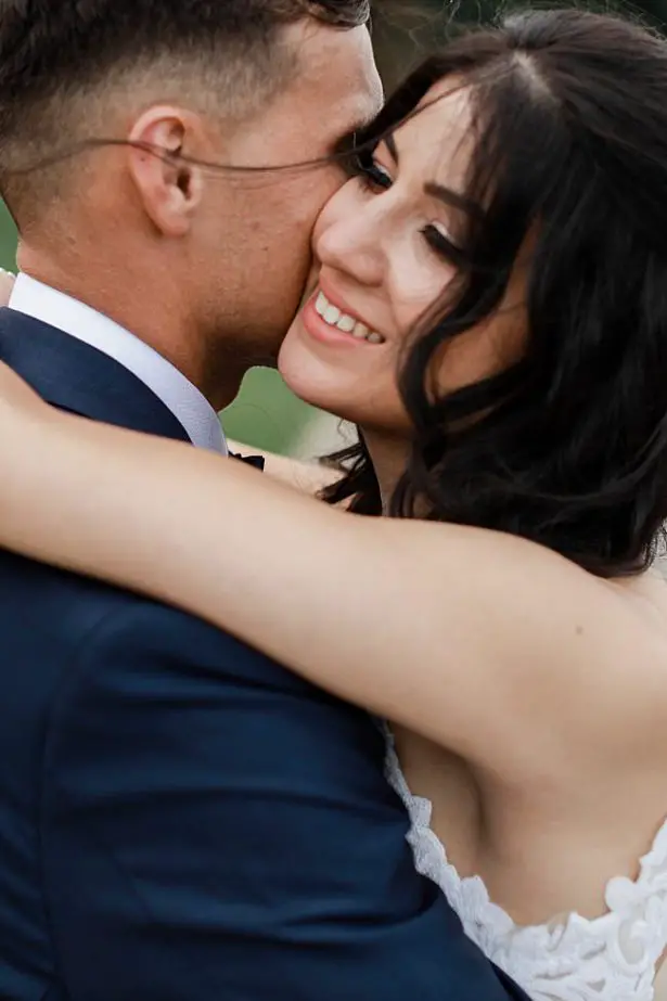 Romantic windswept photo of bride and groom hugging - Bluespark Photography