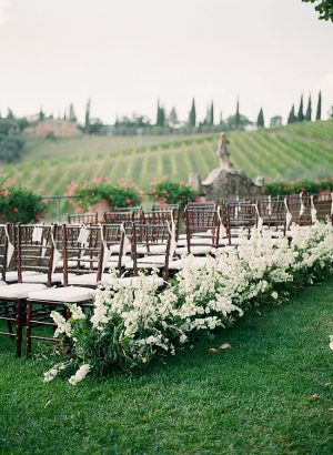 Tuscany Wedding ceremony decor with flowers down the aisle and the rolling hills behind it - Purewhite Photography
