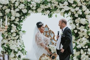 White and Gold Opulent Wedding ceremony with black tie clothing and white floral arch - Photo: Dmitry Shumanev Production