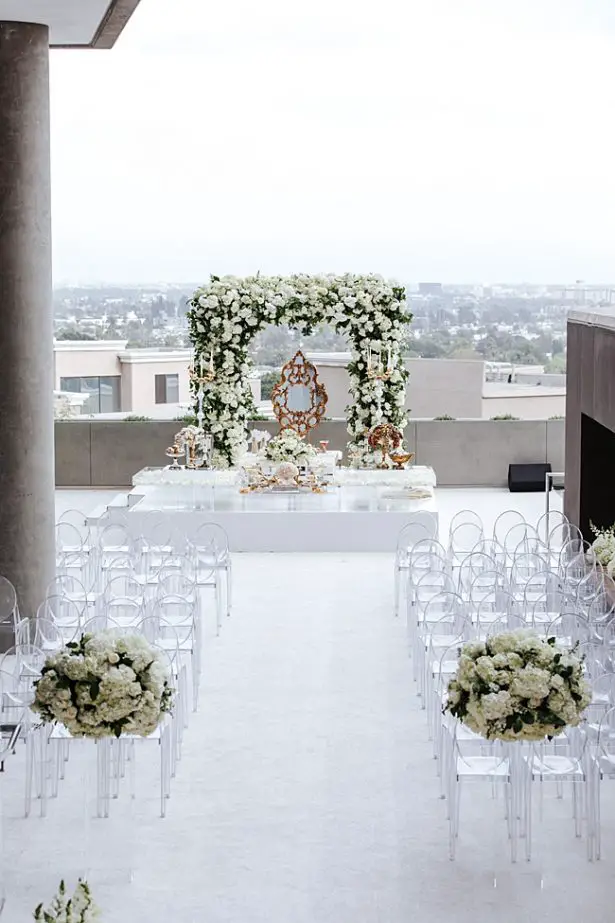 White rooftop Wedding ceremony with floral arch and clear acrylic chairs - Photo: Dmitry Shumanev Production