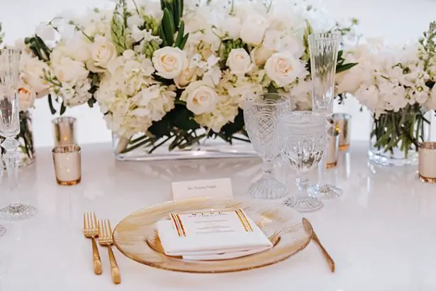 Gold place setting and centerpiece with white flowers - Photo: Dmitry Shumanev Production
